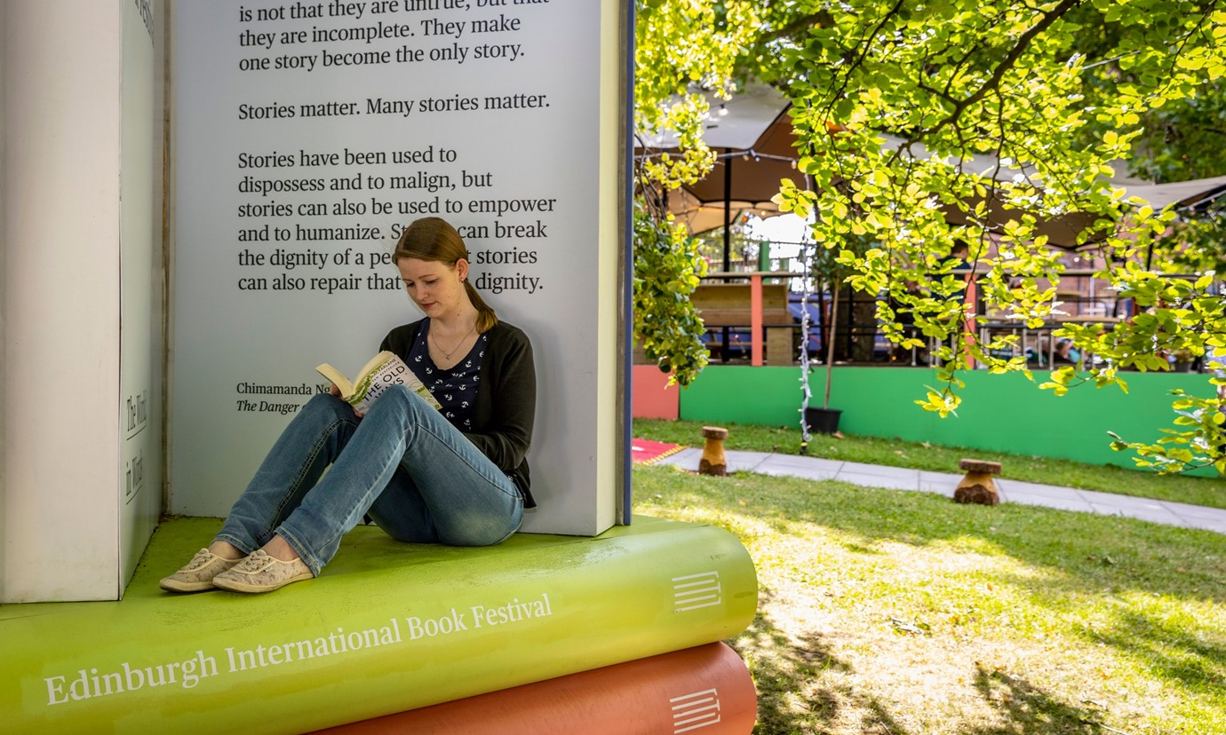Woman sitting on model of books at Edinburgh International Book Festival