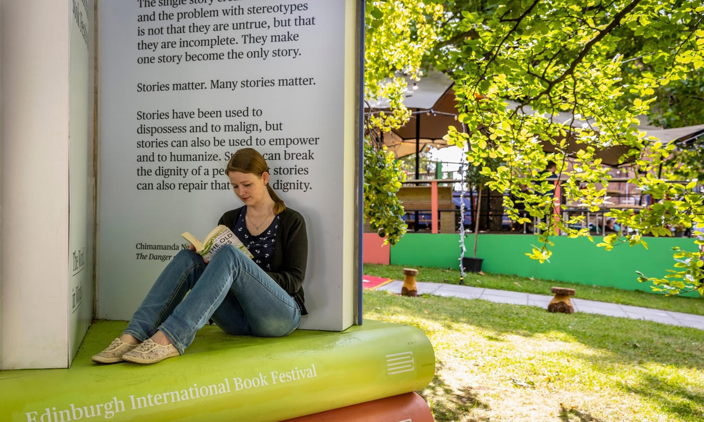 Woman sitting on model of books at Edinburgh International Book Festival