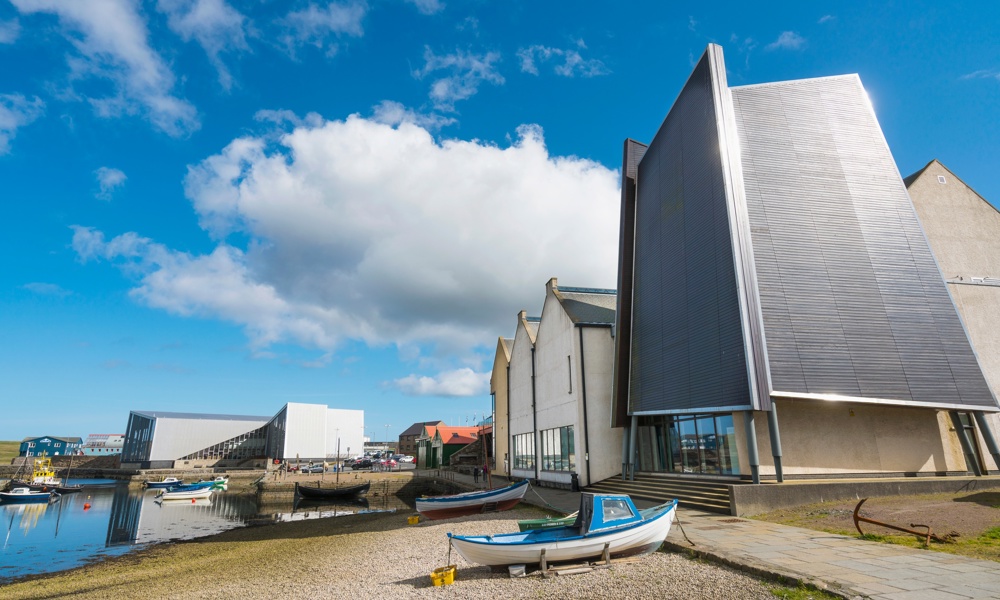 Shetland Museums and Archives sits on the shore with a harboured boat in the foreground