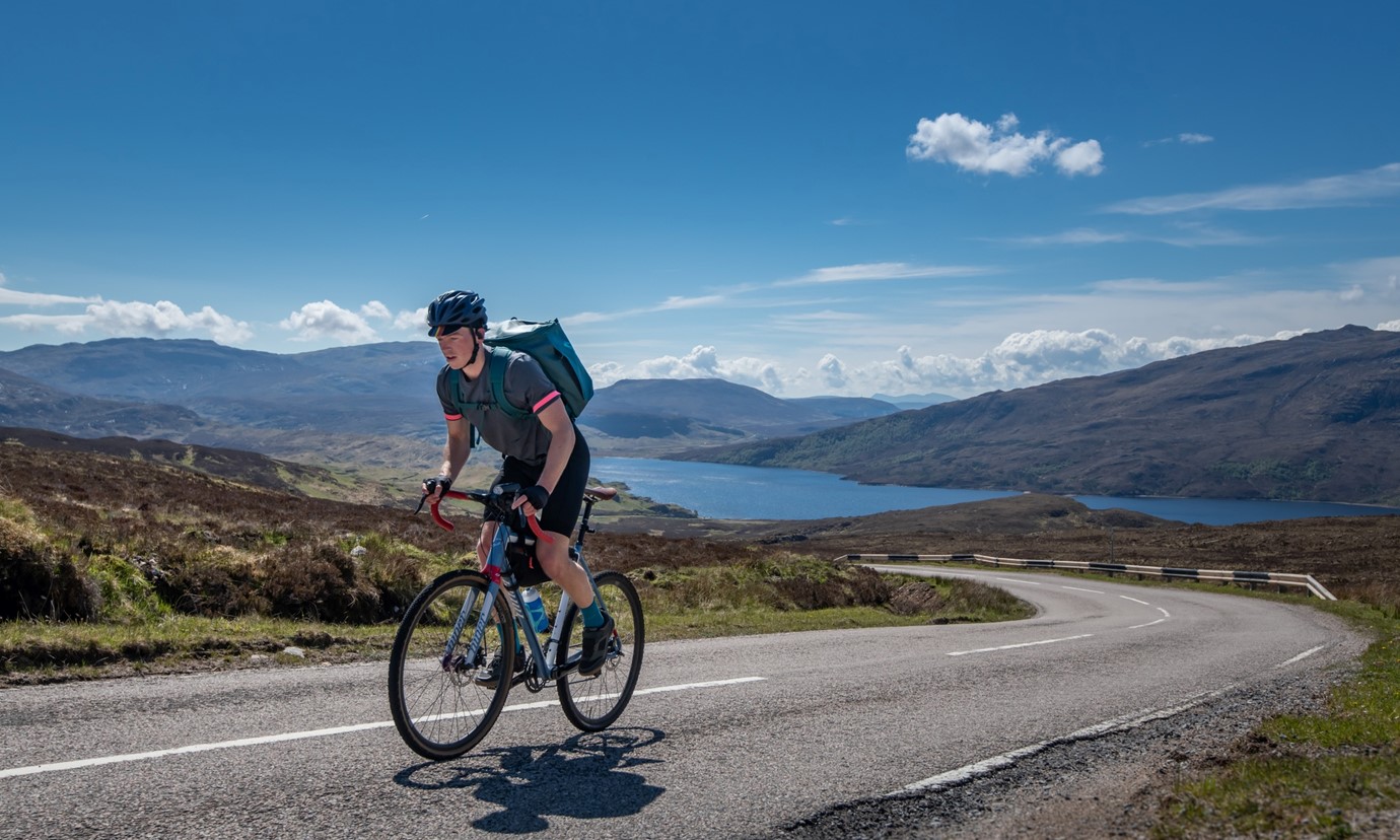 A cyclist travels along the road next to Loch Assynt